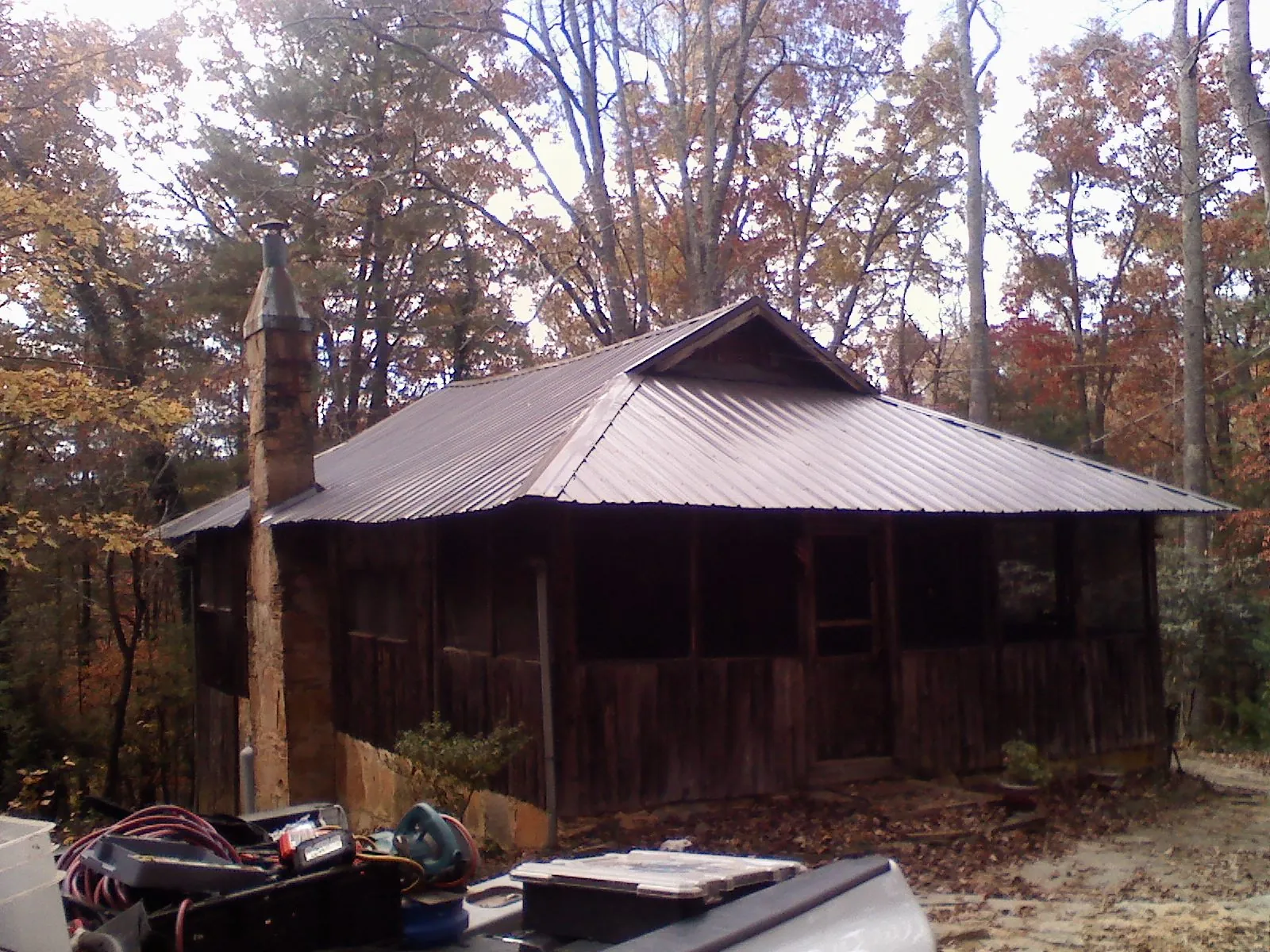 Brown metal hip roof on an old cabin with a stone chimney in Ridgeville